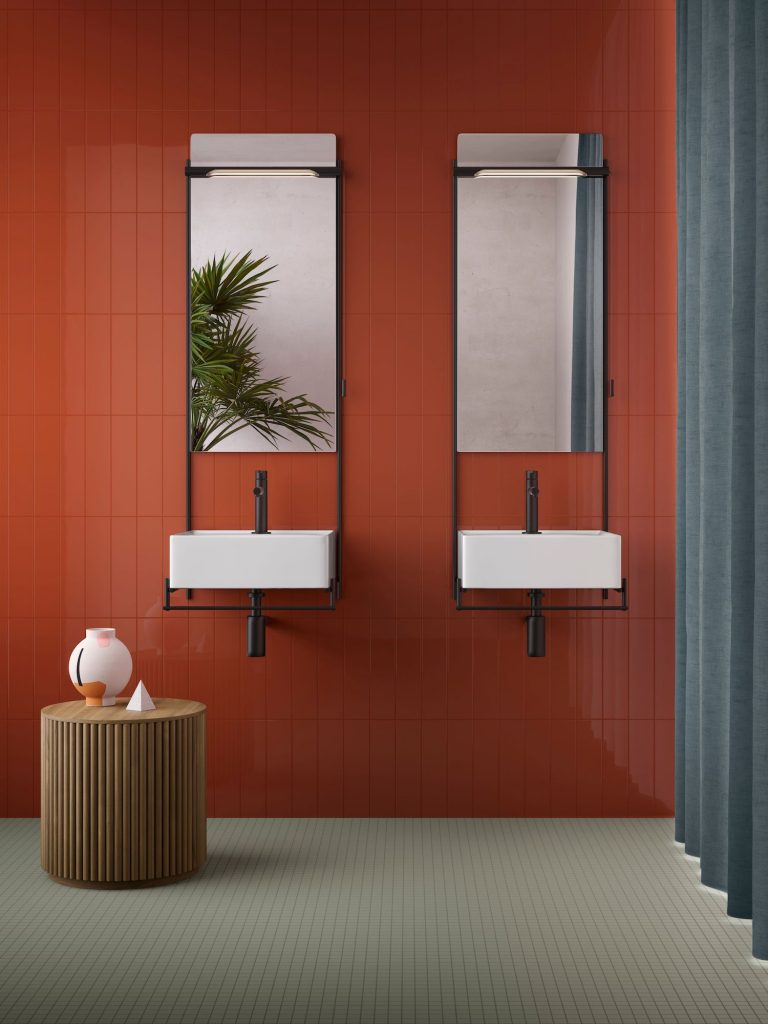 Twin sinks with mirror on red tile background in bathroom