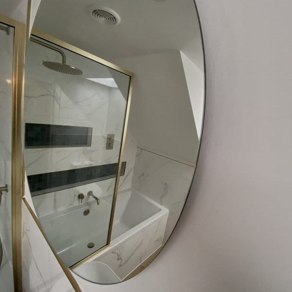 Gold framed shower in marble bathroom